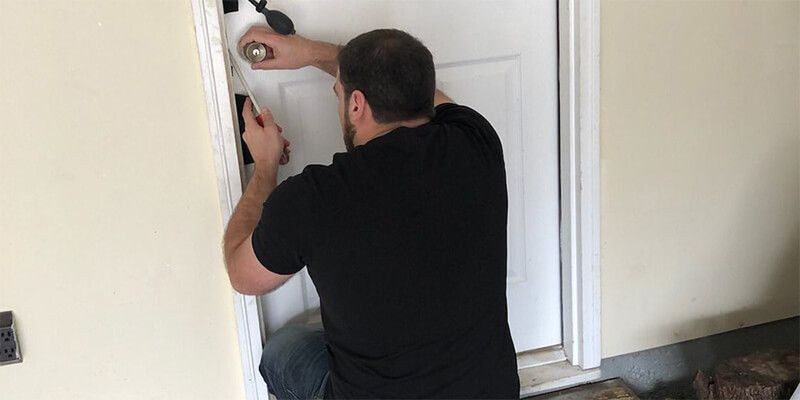 Locksmith providing emergency lockout assistance by unlocking a front door.