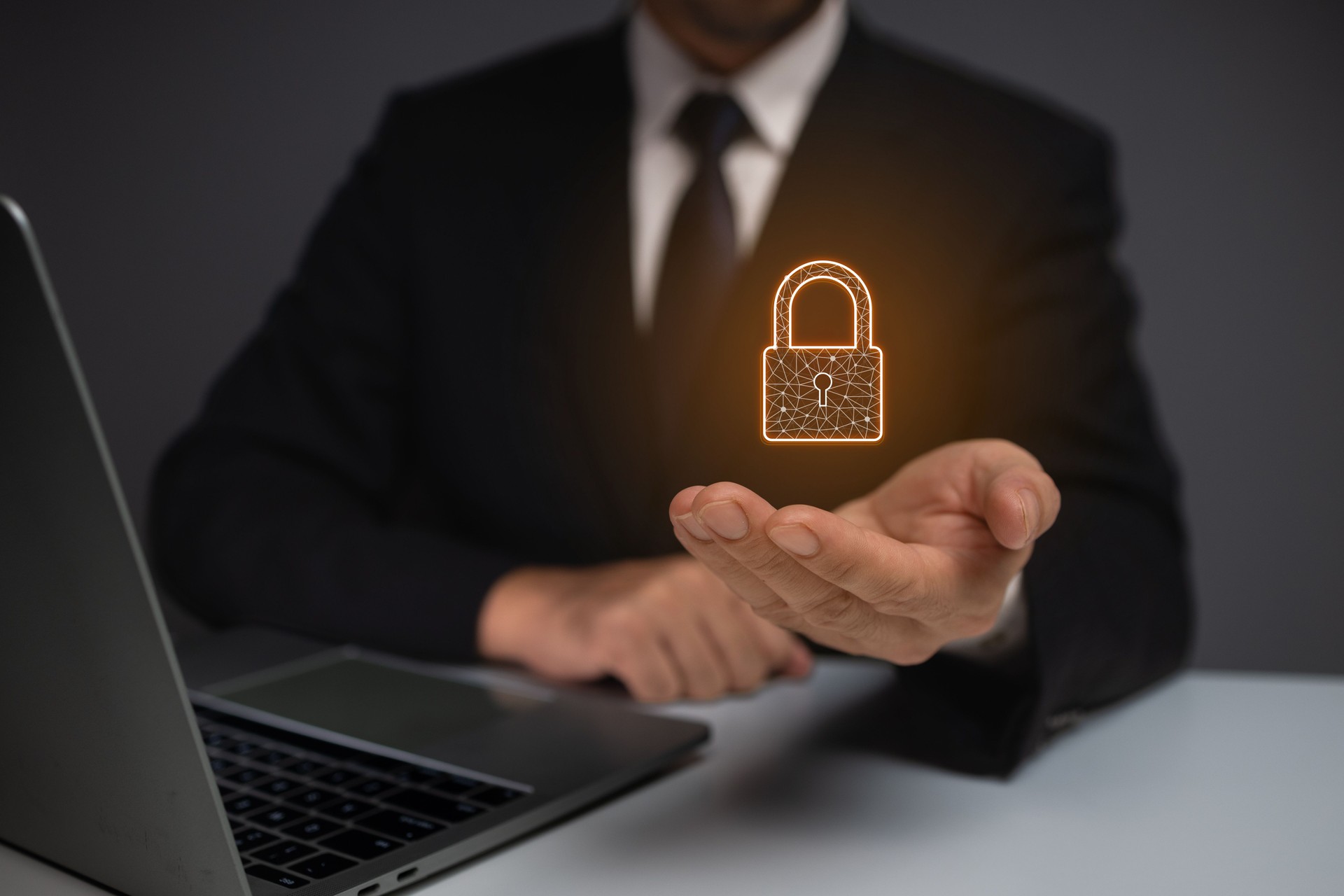 A man is holding a key in his hand and is standing in front of a laptop. Concept of security and protection, as the man is holding a key that could unlock a lock or a safe